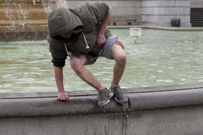 After scavenging for thrown coins in the fountains of Trafalgar Square, a man climbs out of the freezing chemically-treated wate