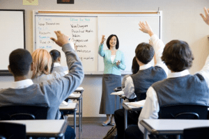 Teacher calling on students with hands raised in a classroom