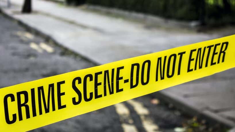 A strip of yellow crime scene tape stretched across a road.