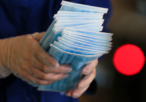 Gloved hands holding face masks