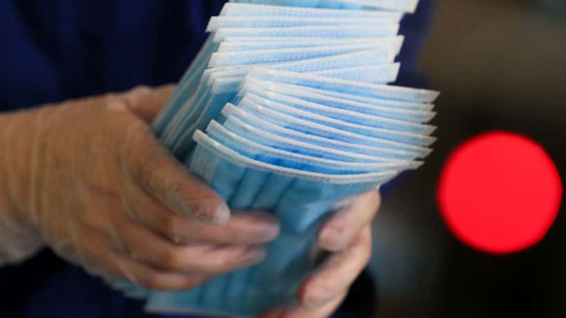 Gloved hands holding face masks