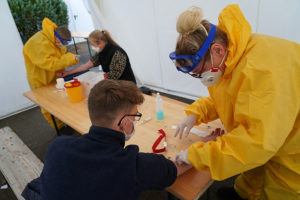 BERLIN, GERMANY - MARCH 27: Medical volunteers dressed in protective suits, masks, gloves and goggles take blood samples from visitors with symptoms to test them for Covid-19 infection in a tent set up next to a doctor's office on March 27, 2020 in Berlin, Germany. Doctor Ulrike Lipke said she set up the tent as a way to offer testing yet avoid possible coronavirus infection inside the premises of her practice. Germany is seeking to radically ramp up its coronavirus testing capacity to up to 200,000 tests per day by the end of April as a means to allow people to return to work and hence get the crisis-stricken German economy back into gear.