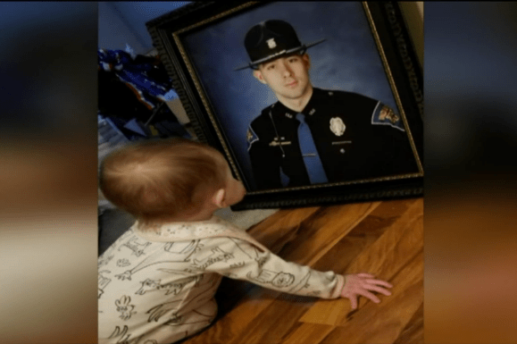 Young child staring at photograph of Indiana State Trooper.