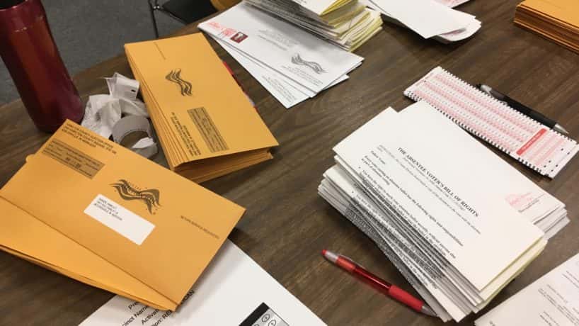 stacks of absentee ballots and envelopes