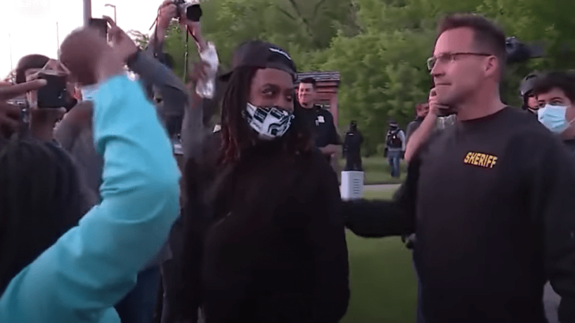 Genesee County Sheriff Chris Swanson drops his baton to join protestors.