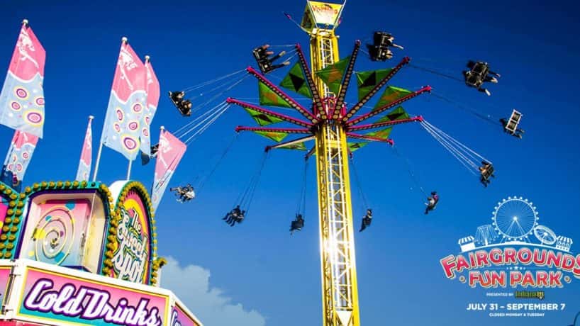 Carnival rides and food vendor under clear blue skies