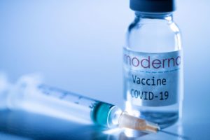 A syringe and a vial of COVID-19 vaccine sits on a doctor's table.