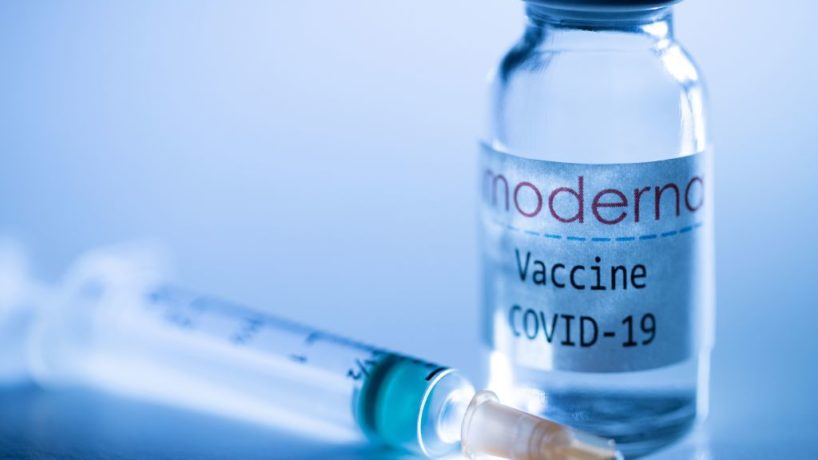 A syringe and a vial of COVID-19 vaccine sits on a doctor's table.