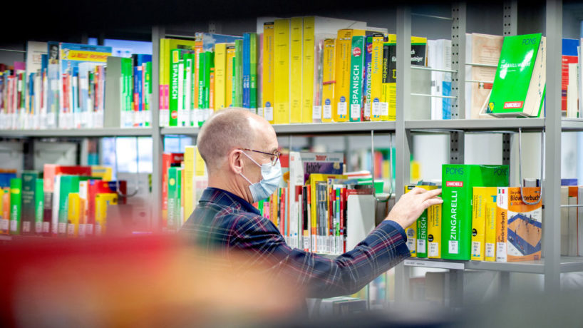 Michael Stünkel, head of the central municipal library, is standing at a shelf with dictionaries in various languages.