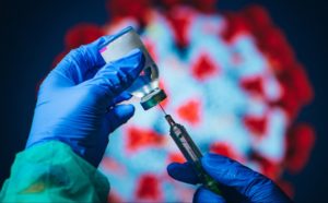 Coronavirus Covid-19 Protection and Vaccine. Doctor drawing up solution from vaccine bottle and filling syringe injection for patient vaccination in medical clinic, Coronavirus in background - stock photo