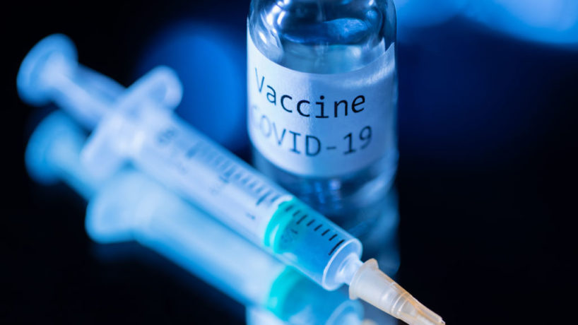 A vial of generic COVID-19 vaccine next to a syringe.