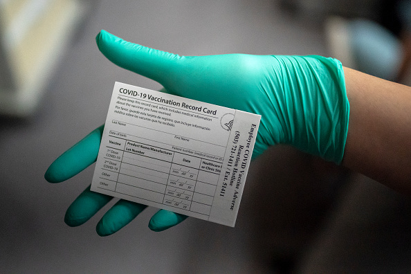 A healthcare worker displays a COVID-19 vaccine record card at the Portland Veterans Affairs Medical Center on December 16, 2020 in Portland, Oregon.