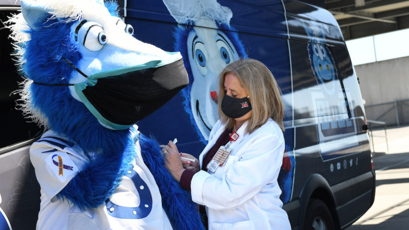 Indianapolis Colts mascot “Blue” at the Indianapolis Motor Speedway to “receive” his COVID-19 vaccination as part of the IMS mass vaccination event. Pictured with him are Dr. Elaine Cox, chief medical officer for Riley Hospital for Children at IU Health; and Mary Kay Foster (black coat), IU Health Special Pathogens program manager. Photographed at the Indianapolis Motor Speedway on 04/26/21.