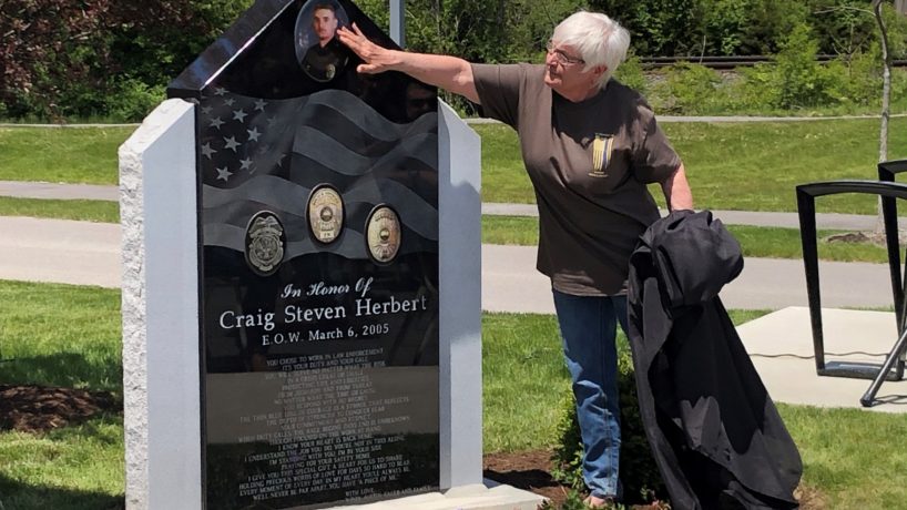 Andy Macy, mother of fallen Lawrence police officer Craig Herbert, touches her son's photograph on a memorial monument unveiled at Lawrence police headquarters.