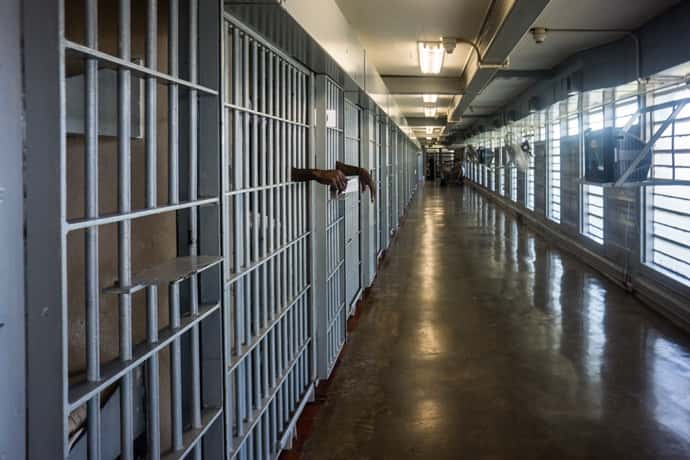 The interior hallway of a prison with cells on the left.