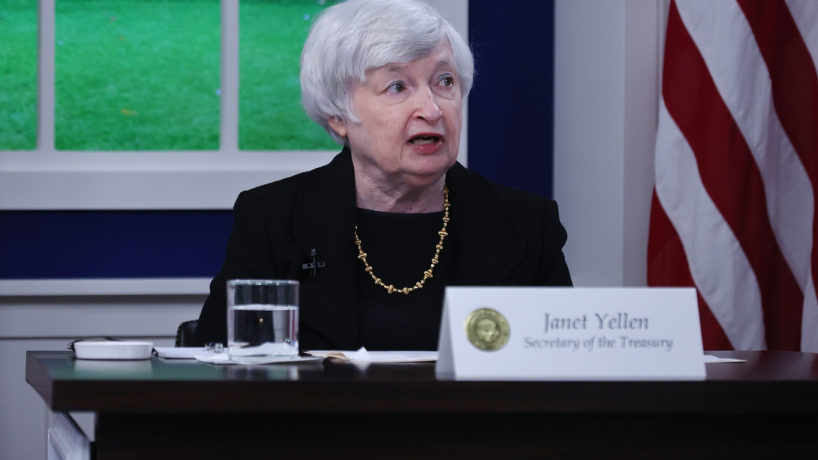 Yellen sitting in front of an American Flag with name tag