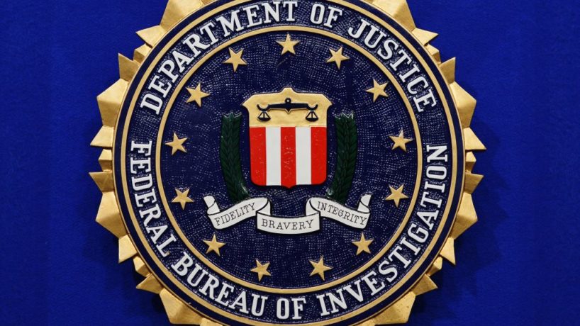 The Federal Bureau of Investigation (FBI) seal is seen on the lectern.