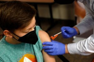 Aiden Arthurs receives the Pfizer-BioNTech Covid-19 Vaccine from Pharmacist Andrew Mac (R) at the Jewish Federation/JARC's offices in Bloomfield Hills, Michigan, on May 13, 2021.