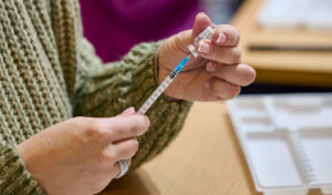 A mask-clad health technician prepares doses of Pfizer-BioNTech COVID-19 vaccine.