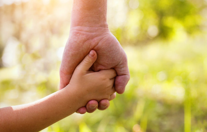 A child and parent holding hands.