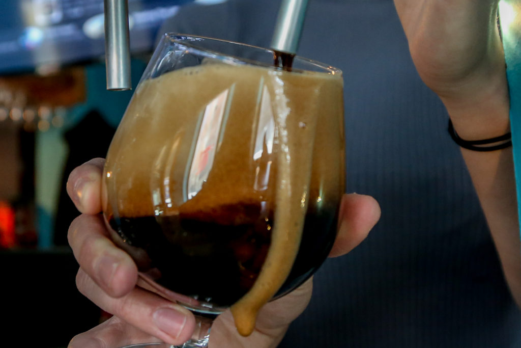 stout beer being poured into glass