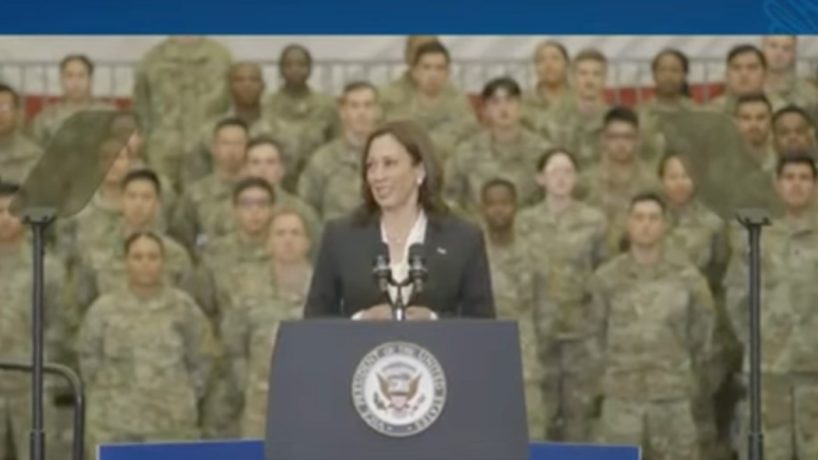 A screen capture shows Kamala Harris speaking to a group of troops.