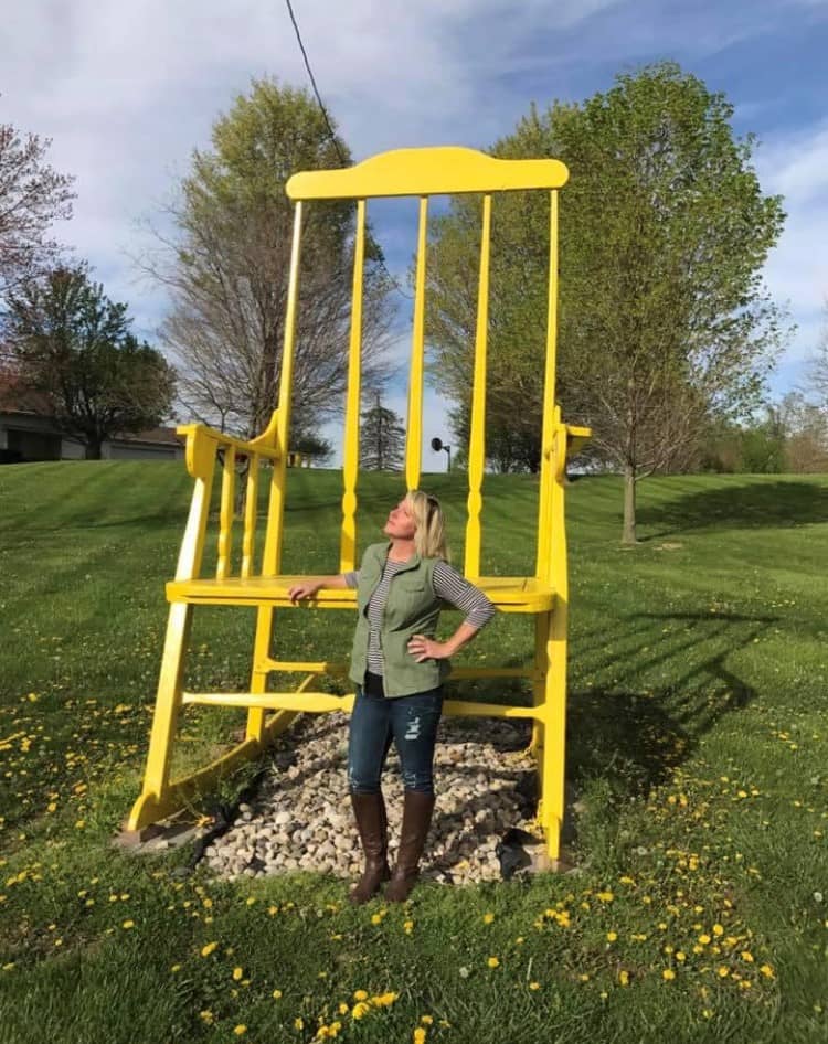woman standing in front of large, bright yellow rocking chair