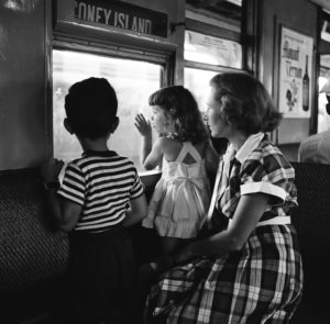 black and white photo of mother with son and daughter looking out window