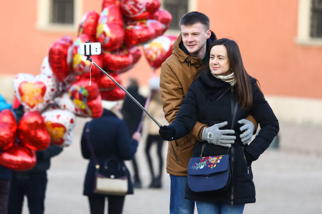 man standing behind woman with arms around her waist taking a selfie picture