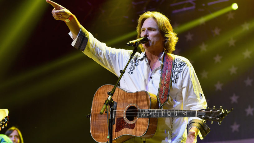 Country music star Billy Dean on stage with guitar pointing to the crowd