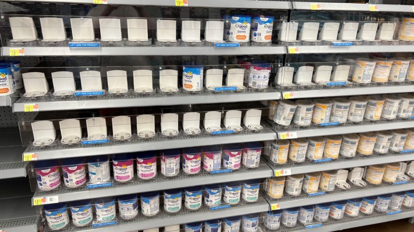 This is a picture a baby formula rack at a grocery store. The image shows many empty spots, due to a formula shortage.