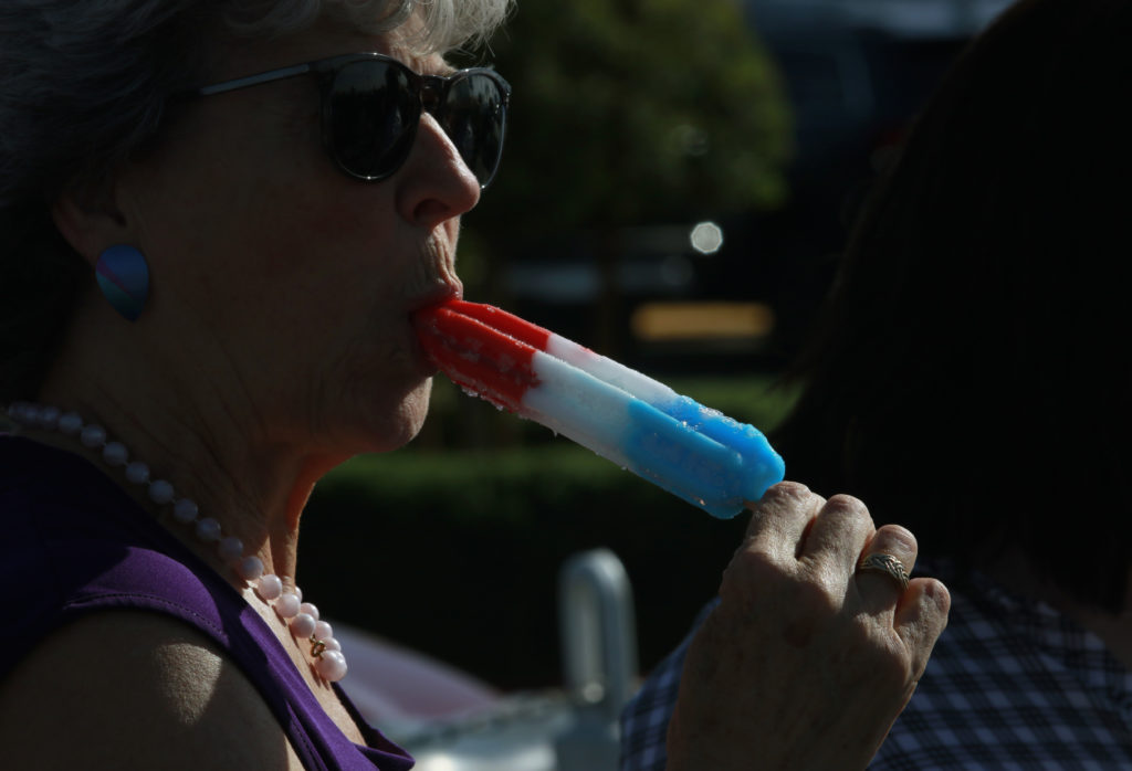 A woman eats a red, white and blue popsicle