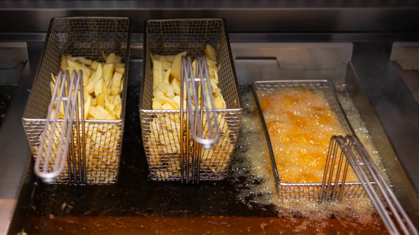 Chips being cooked in a deep fat fryer in a British fish