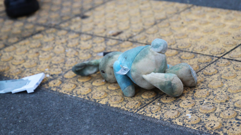 A stained and dirty child's soft toy lies on the ground