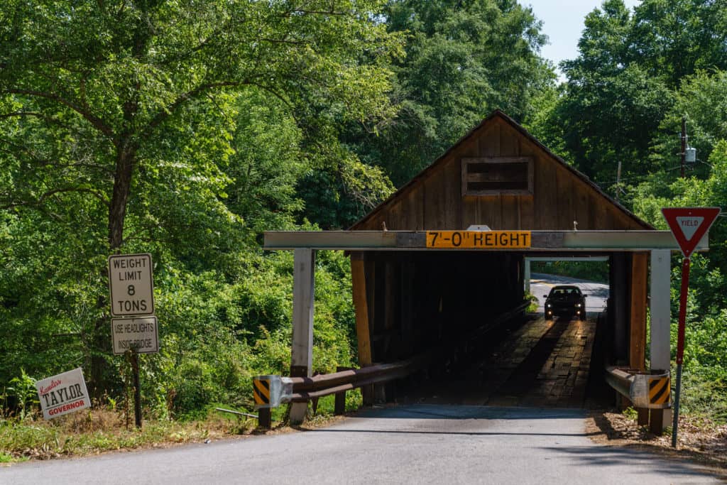 A vehicle drives through a historic covered bridge