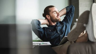Relaxed smiling businessman sitting in office with closed eyes