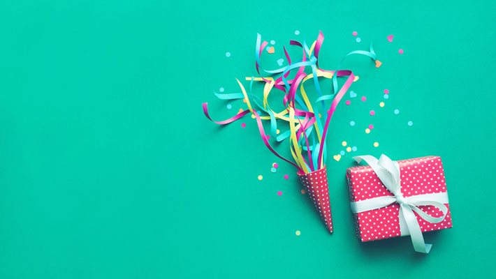 Colorful confetti,streamers and gift box on a teal background