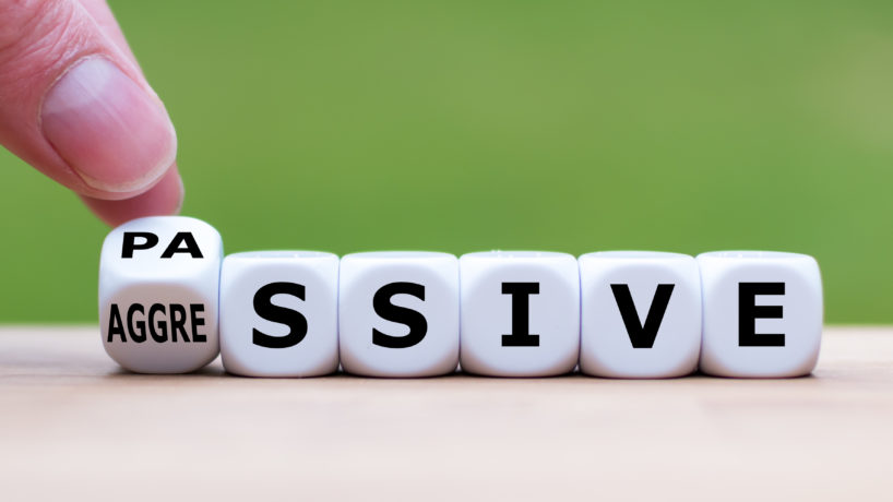 Hand turns a dice and changes the word "passive" to "aggressive", or vice versa