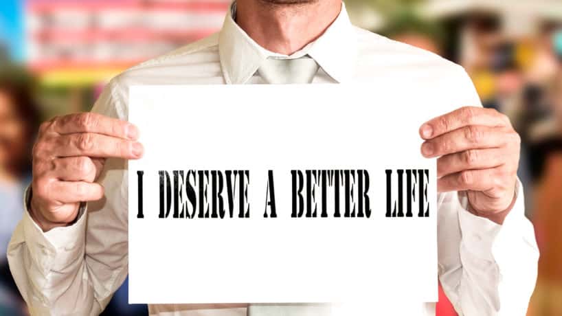 Man with shirt and tie has a banner with the word I deserve a better life.
