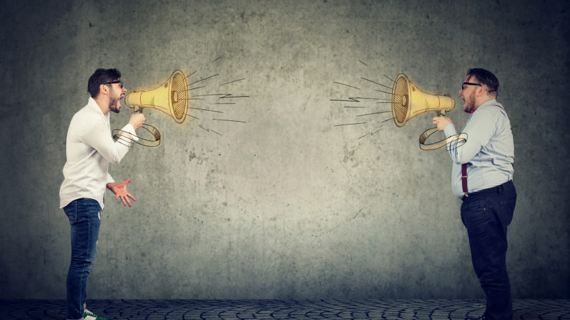 Businessmen screaming into a megaphone at each other having an angry debate