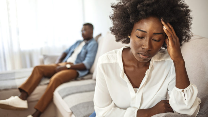 Unhappy Couple After an Argument in the Living Room at Home. Sad Pensive Young Girl Thinking of Relationships Problems Sitting on Sofa With Offended Boyfriend, Conflicts in Marriage,