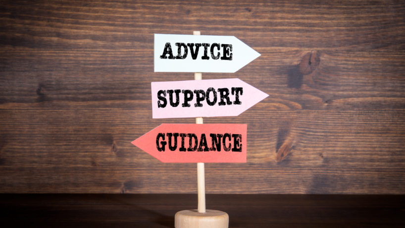 Signpost with arrows - Advice, Support and Guidance. Customer support, teamwork and education concept. Dark wood background