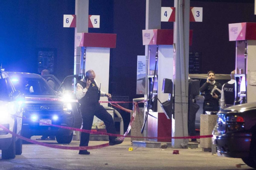 Chicago police officers investigate a shooting incident at a gas station in Lyons, Il., Wednesday, Oct. 20, 2021. An officer accidentally fired his handgun during a struggle while police were making arrests in suburban Chicago, wounding two other officers, authorities said. (Steven Rosenberg/Chicago Tribune via AP)