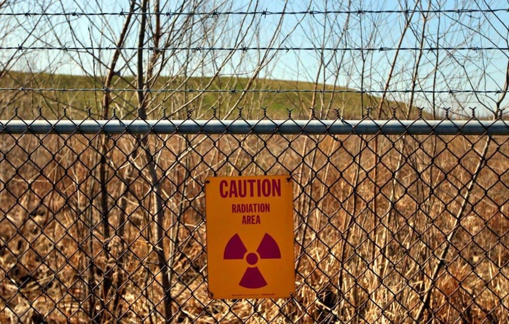 FILE - A radiation warning sign hangs on a fence at the West Lake landfill in Bridgeton, Mo., March 13, 2012. The Environmental Protection Agency said Friday, March 18, 2022, that a project to remove nuclear waste from the landfill has been delayed in part because more atomic waste was found at the site. The waste is especially concerning because it sits a few hundred yards from underground smoldering at an adjacent landfill. EPA spokesman Ben Washburn said it isn't uncommon to find additional contamination at a Superfund site once a remediation project begins. (Laurie Skrivan/St. Louis Post-Dispatch via AP, File)