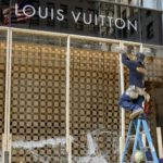 FILE - Workers begin to board up a display window at the Louis Vuitton store Monday, Aug. 10, 2020, after overnight vandals hit many high-end stores in Chicago. The Illinois Senate has a bipartisan plan to crack down on a recent spate of smash-and-grab retail thefts and the fencing that follows. Bill sponsor Western Springs Democratic Sen. Suzy Glowiak Hilton says smash-and-grab crimes not only result in product loss but terrorize employees and patrons and damage property. (AP Photo/Teresa Crawford, File)