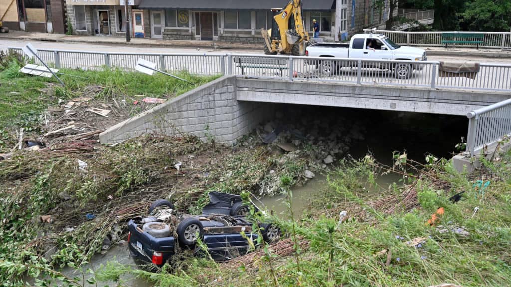 A car lays overturned in Troublesome Creek in downtown Hindman, Ky., Sunday, July 31, 2022. (AP Photo/Timothy D. Easley)