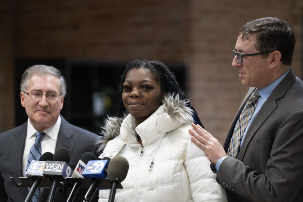 Attorney Russell Ainsworth, right, encourages 18-year-old Janiah Caine, who was previously in the care of Illinois Department of Children and Family Services as a minor, to "speak from the heart" during a press conference announcing a class action lawsuit alleging the DCFS has wrongfully incarcerated minors in its care. Thursday, Jan. 19, 2023, at the offices of Loevy & Loevy Attorneys at Law in Chicago. Caine spoke about the consequences of being locked up for so long, and about losing her grandmother while she was incarcerated. (AP Photo/Erin Hooley)