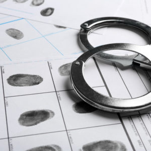 handcuffs-and-fingerprint-record-sheets-closeup-criminal-investigation