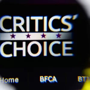 Photo of Critics' Choice Awards homepage on a monitor screen through a magnifying glass.