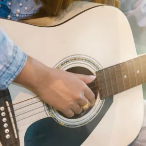 Close up woman's hands playing acoustic guitar.